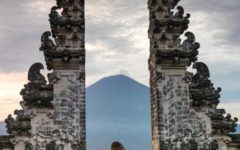 person in red jacket standing in front of brown concrete building during daytime