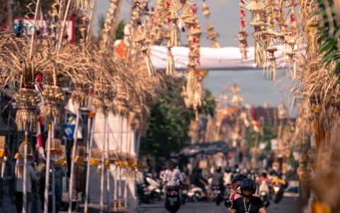 Street adorned with balinese decorations and scooters.